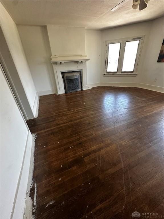 unfurnished living room featuring ceiling fan and dark hardwood / wood-style flooring