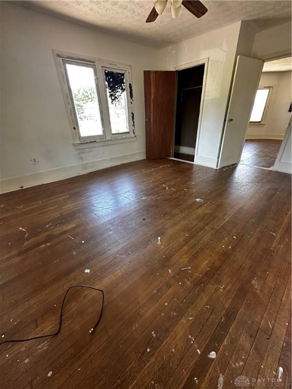 interior space with a textured ceiling, ceiling fan, and dark wood-type flooring