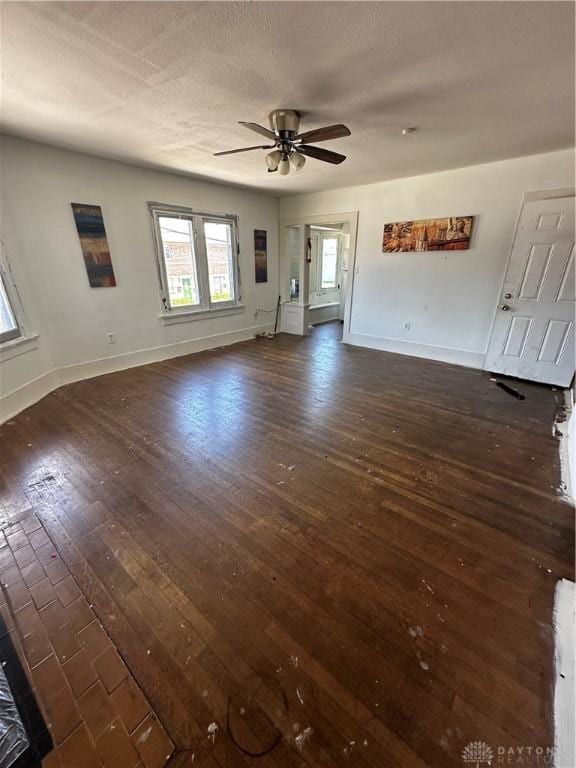 unfurnished living room featuring a textured ceiling, ceiling fan, and dark wood-type flooring