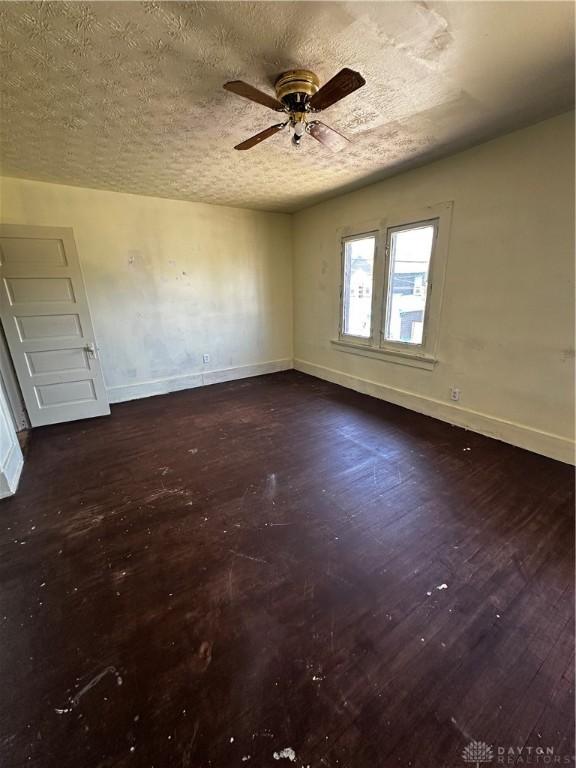 unfurnished room featuring a textured ceiling, ceiling fan, and dark hardwood / wood-style floors