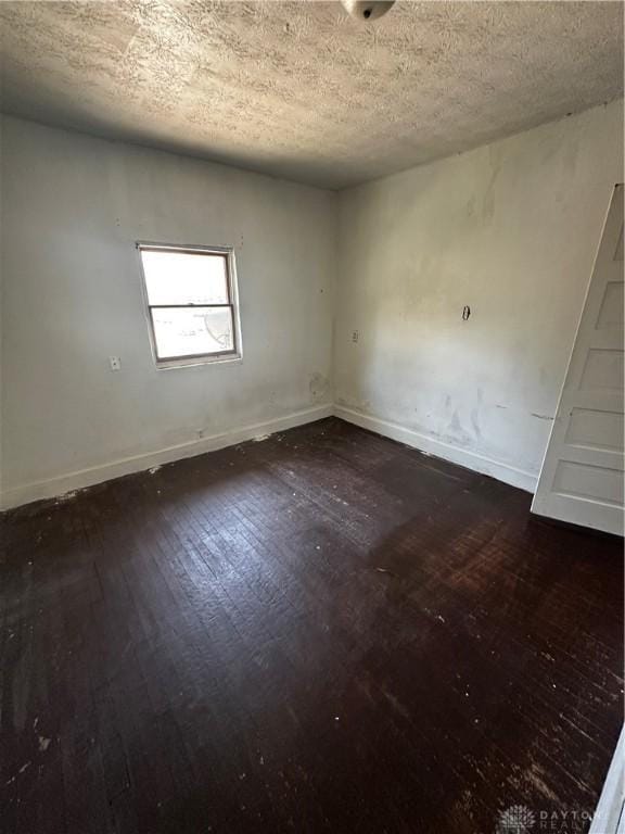 spare room featuring a textured ceiling and dark hardwood / wood-style floors