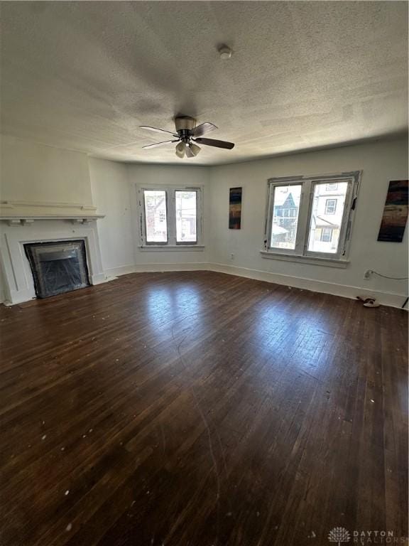 unfurnished living room with dark hardwood / wood-style floors, ceiling fan, and a textured ceiling