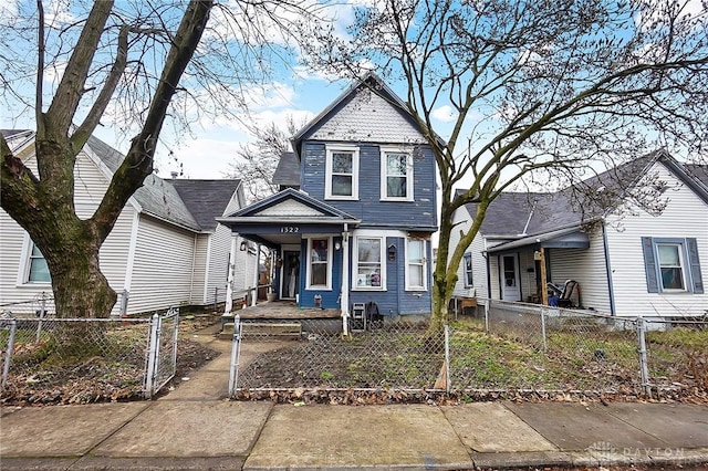 victorian home with a fenced front yard, a gate, and covered porch