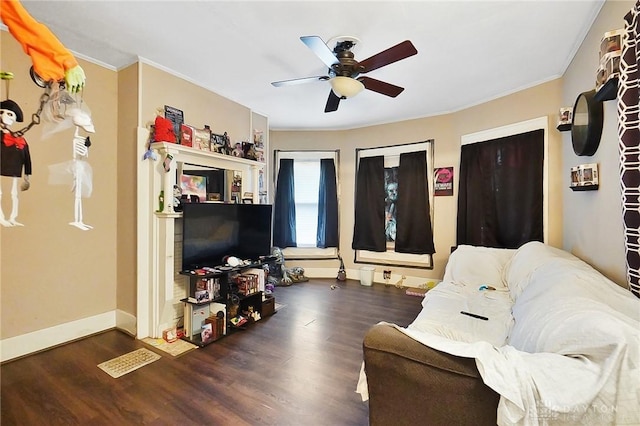 living area with crown molding, dark wood finished floors, baseboards, and ceiling fan