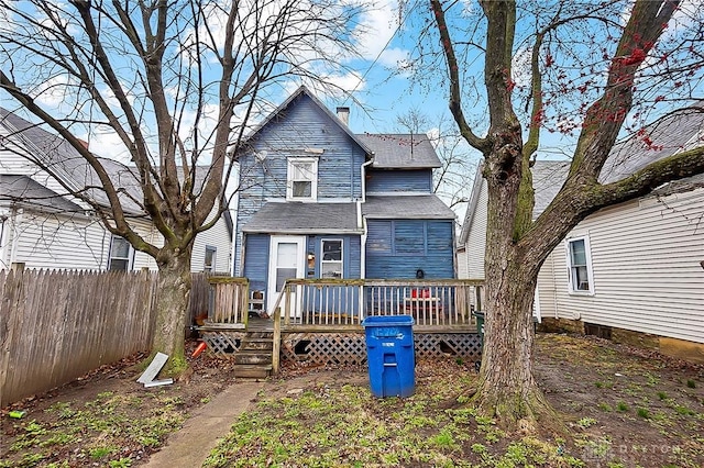 rear view of house with a chimney, fence, and a wooden deck