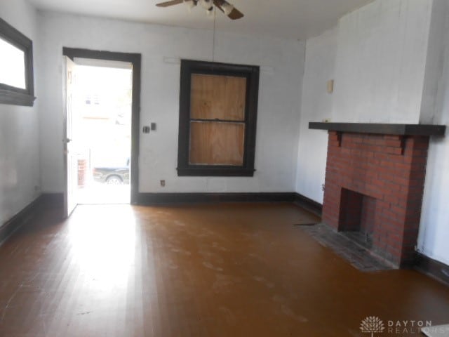 unfurnished living room featuring a brick fireplace, ceiling fan, and dark hardwood / wood-style floors