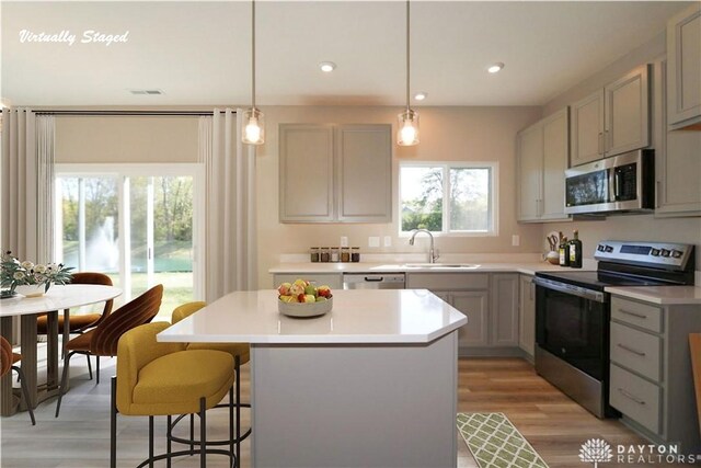 kitchen featuring gray cabinets, stainless steel appliances, a sink, and a center island