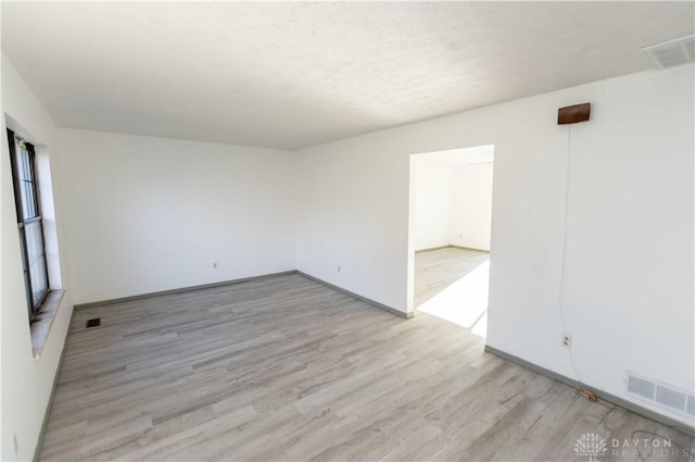 unfurnished room with light hardwood / wood-style floors and a textured ceiling