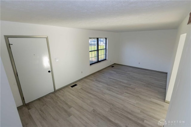 unfurnished room featuring light hardwood / wood-style floors and a textured ceiling