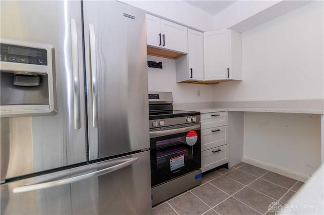 kitchen with tile patterned floors, stainless steel appliances, and white cabinets