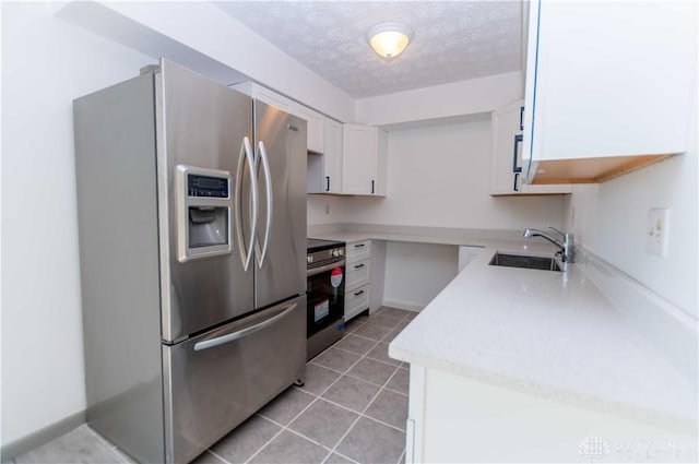 kitchen with sink, light tile patterned floors, stainless steel appliances, white cabinets, and a textured ceiling