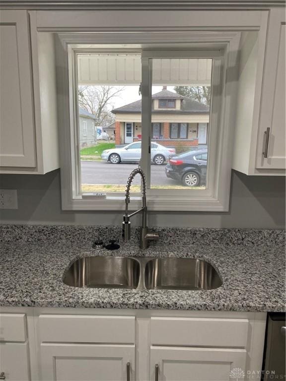 kitchen with white cabinets, light stone countertops, and sink