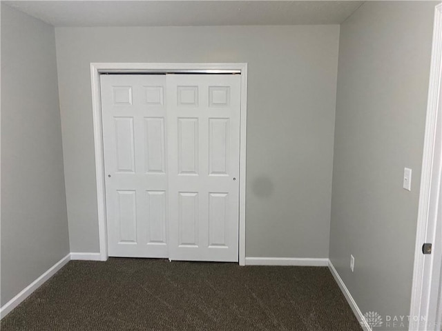 unfurnished bedroom featuring dark colored carpet and a closet