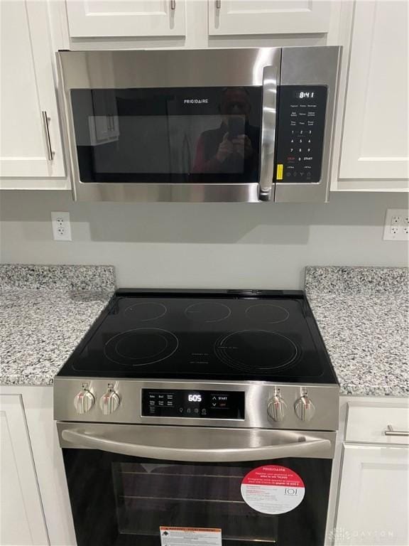 details featuring white cabinets, light stone counters, and stainless steel appliances