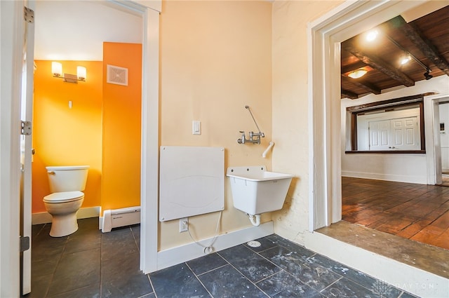 bathroom featuring beamed ceiling, sink, toilet, baseboard heating, and tile patterned flooring