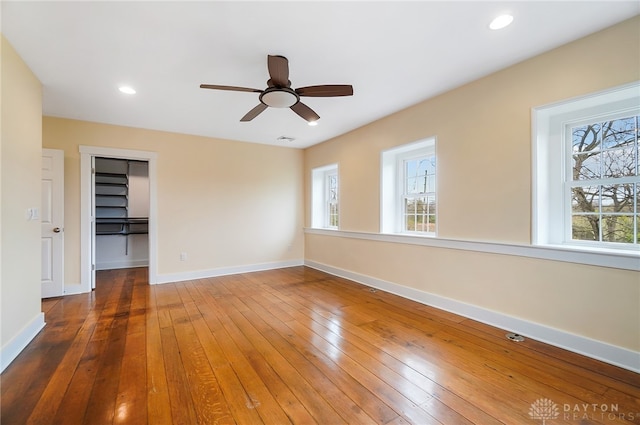 unfurnished bedroom featuring a closet, multiple windows, ceiling fan, and hardwood / wood-style floors