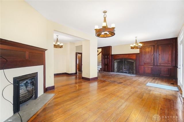 unfurnished living room with hardwood / wood-style flooring and a chandelier