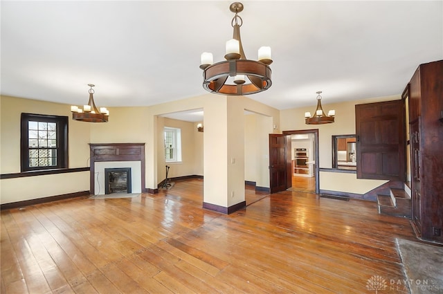 unfurnished living room featuring wood-type flooring and a notable chandelier