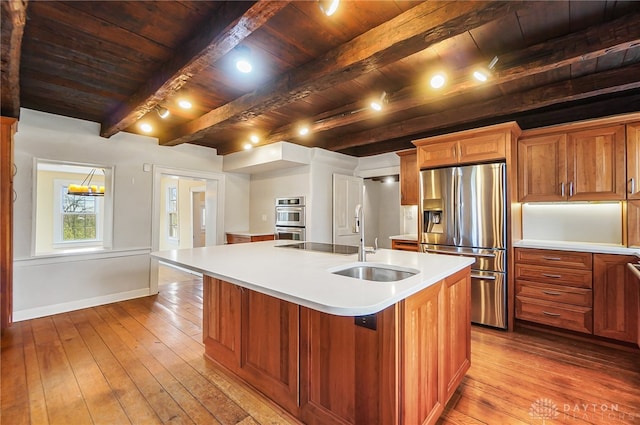 kitchen featuring stainless steel appliances, an island with sink, beamed ceiling, sink, and wood ceiling