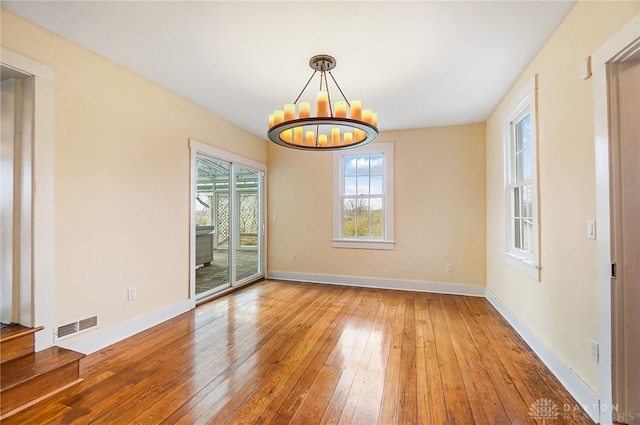 empty room featuring hardwood / wood-style flooring and an inviting chandelier