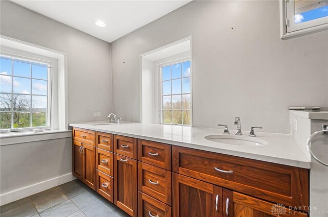 bathroom with dual vanity, tile patterned flooring, and a healthy amount of sunlight