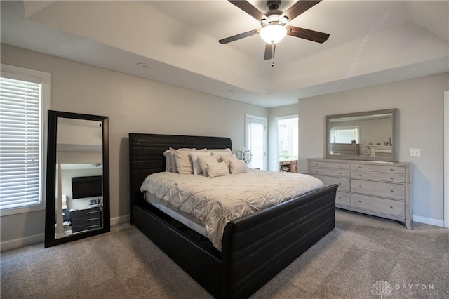 bedroom featuring ceiling fan, multiple windows, carpet flooring, and a tray ceiling