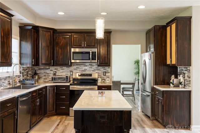 kitchen with pendant lighting, stainless steel appliances, light hardwood / wood-style floors, decorative backsplash, and sink