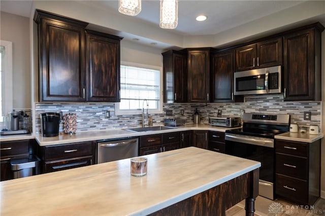 kitchen featuring appliances with stainless steel finishes, backsplash, dark brown cabinets, and sink