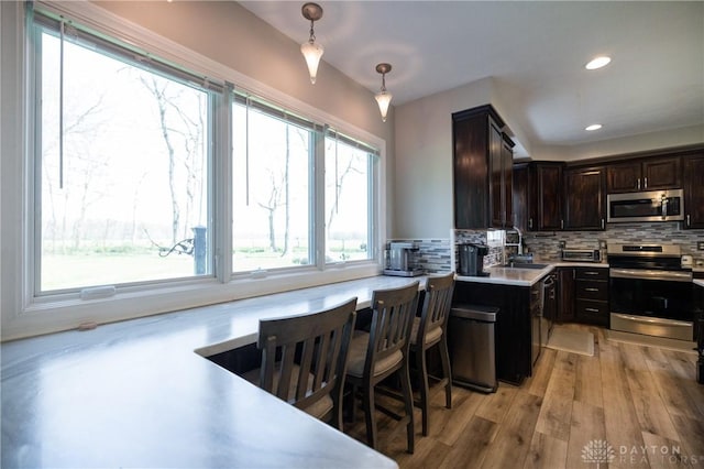 kitchen with appliances with stainless steel finishes, pendant lighting, a healthy amount of sunlight, and decorative backsplash