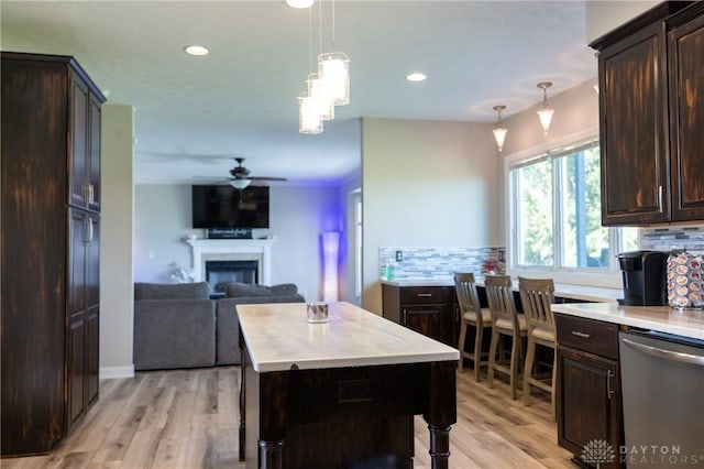 kitchen featuring stainless steel dishwasher, a kitchen island, decorative light fixtures, and tasteful backsplash