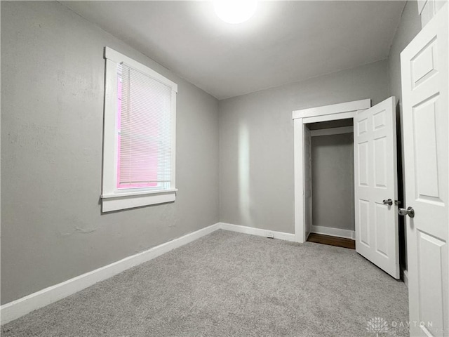 unfurnished bedroom with light colored carpet and a closet