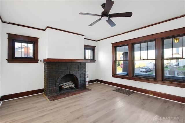 unfurnished living room featuring a brick fireplace, light hardwood / wood-style flooring, ceiling fan, and crown molding