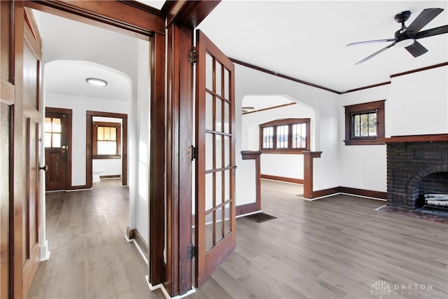 hall with light hardwood / wood-style floors, crown molding, and a healthy amount of sunlight