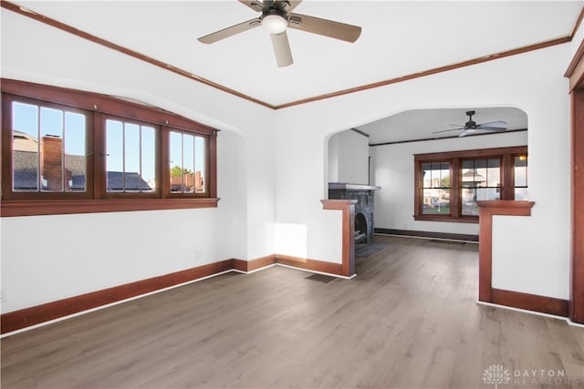 unfurnished living room featuring hardwood / wood-style flooring, plenty of natural light, crown molding, and ceiling fan