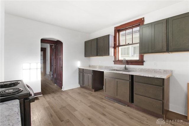 kitchen featuring black / electric stove, dark brown cabinetry, sink, and light hardwood / wood-style floors