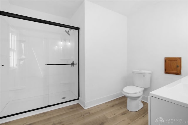 bathroom with wood-type flooring, toilet, and a shower with shower door