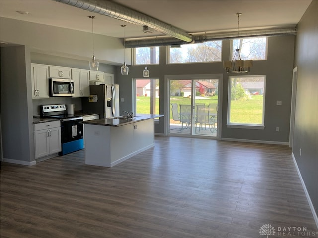 kitchen with white cabinetry, a high ceiling, dark hardwood / wood-style floors, appliances with stainless steel finishes, and decorative light fixtures