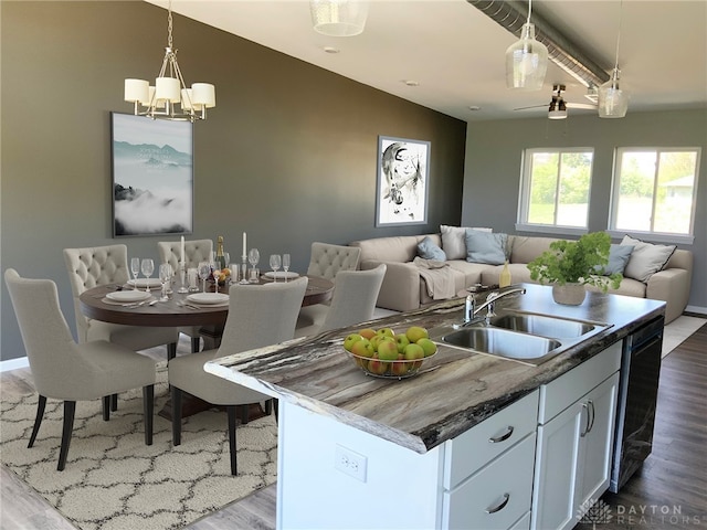 kitchen featuring dishwashing machine, dark hardwood / wood-style flooring, a kitchen island with sink, and sink