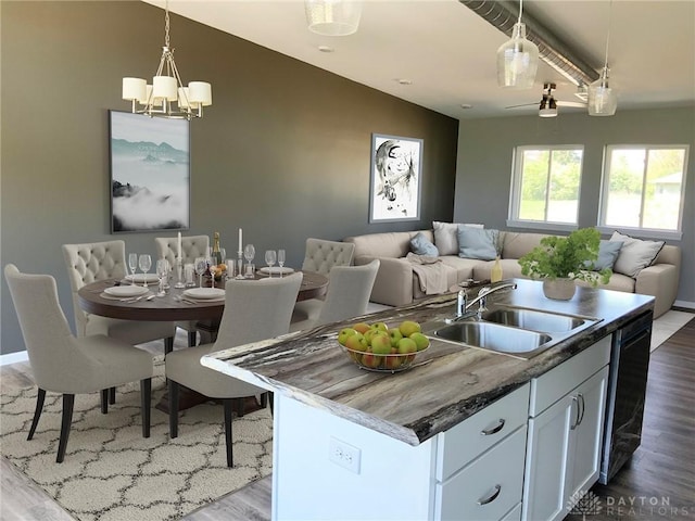 kitchen with a sink, white cabinetry, open floor plan, an island with sink, and decorative light fixtures