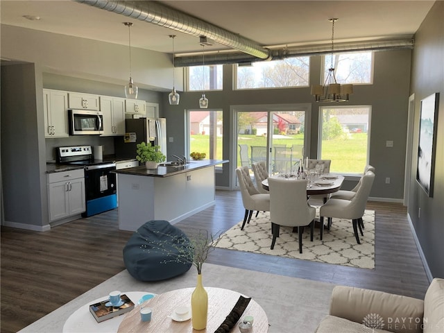 dining room featuring dark wood-type flooring, a towering ceiling, and a wealth of natural light