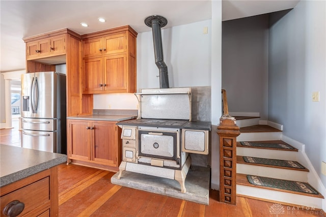 2696 Wilmington Rd, Lebanon, OH 45036 - kitchen with recessed lighting, brown cabinets, stainless steel fridge with ice dispenser, a wood stove, and light wood-type flooring