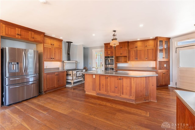 2696 Wilmington Rd, Lebanon, OH 45036 - kitchen with stainless steel appliances, a kitchen island with sink, dark wood-style floors, brown cabinetry, and light countertops