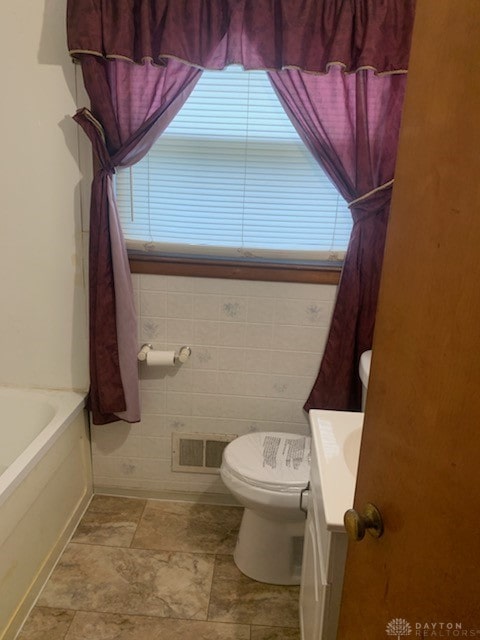 full bathroom with tile patterned flooring, toilet, vanity, tile walls, and  shower combination