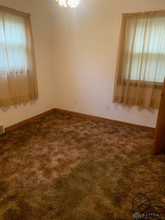 spare room with dark colored carpet