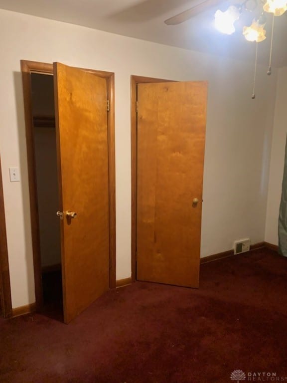 unfurnished bedroom with two closets, dark colored carpet, and ceiling fan