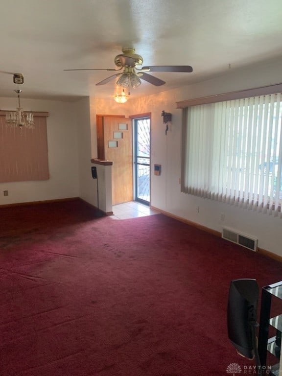 unfurnished living room with ceiling fan with notable chandelier and carpet