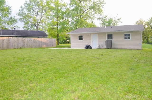 rear view of property with a yard and central air condition unit