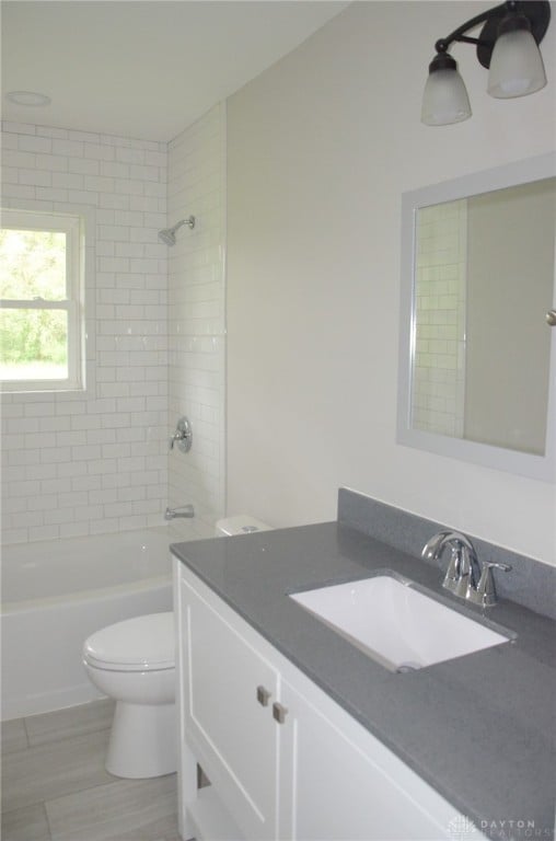 full bathroom featuring toilet, tiled shower / bath, hardwood / wood-style floors, and vanity