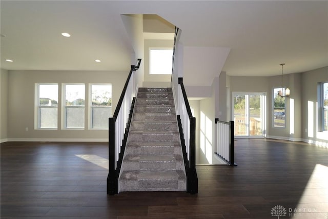 stairway featuring recessed lighting, a notable chandelier, baseboards, and wood finished floors