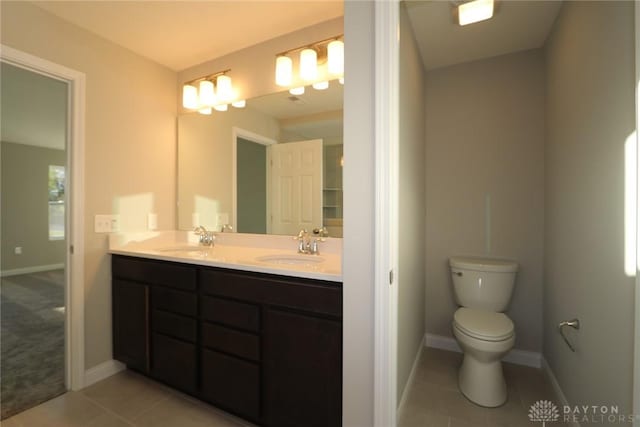 bathroom featuring double vanity, tile patterned flooring, a sink, and toilet